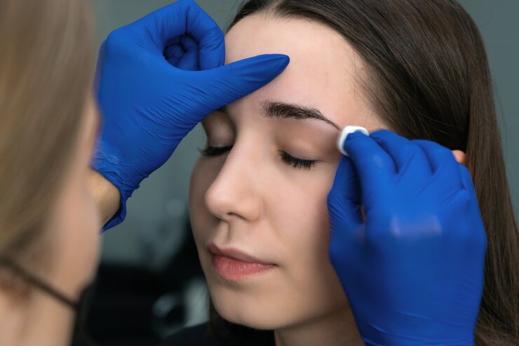 Young woman tweezing her eyebrows in beauty saloon.
